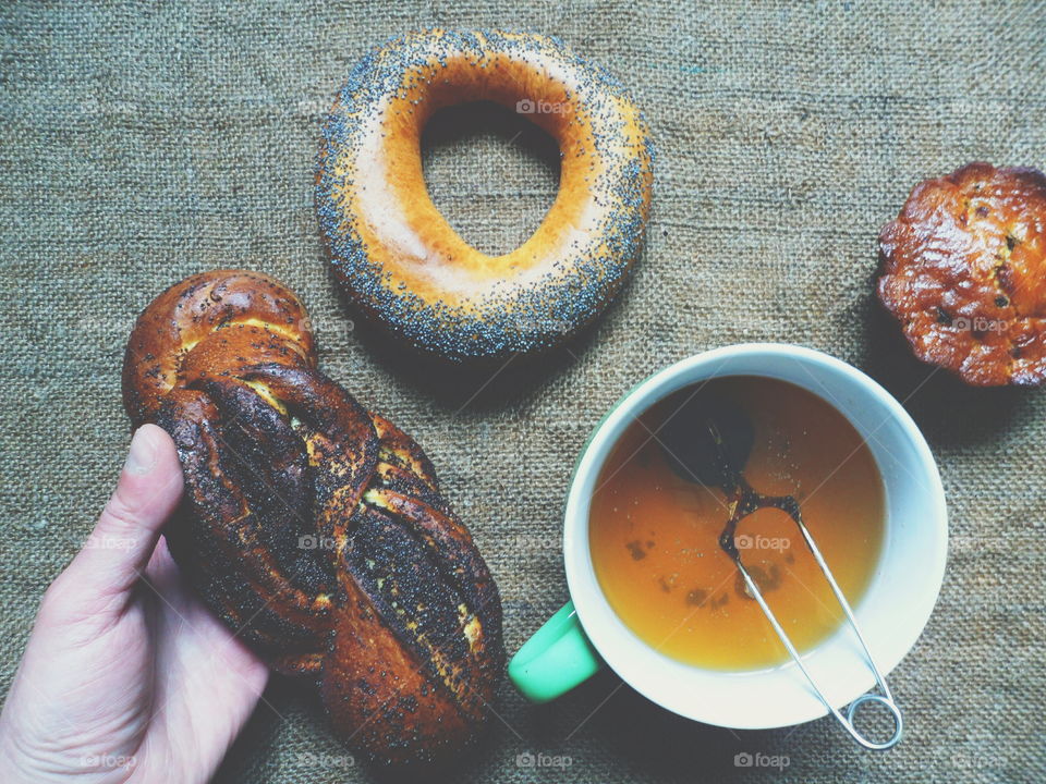 bagel with poppy seeds, basket with poppy seeds, vanilla cupcake and a cup of tea on the table