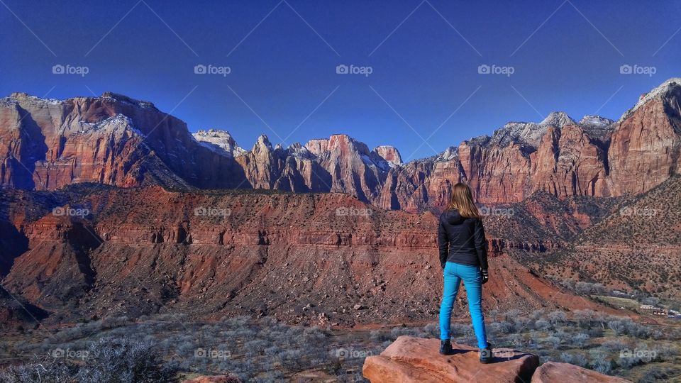 young woman looks over the red rock mountains of Zion National Park in Utah