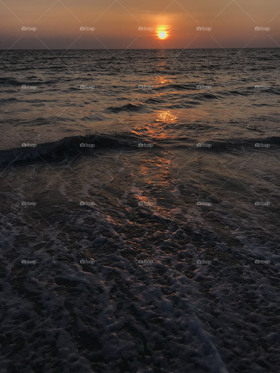 scene of sunset with its light reflects above the sea and amazing wave at Phuket beach, Thailand