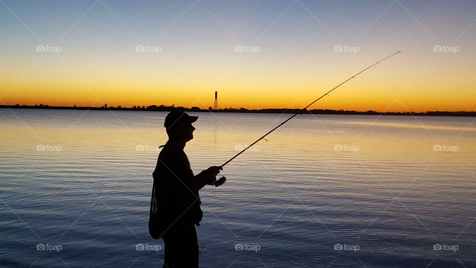 Silhouette of man fishing at lake