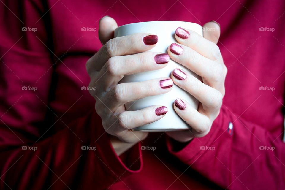 Woman's hands with beautiful manicure are holding a white cup