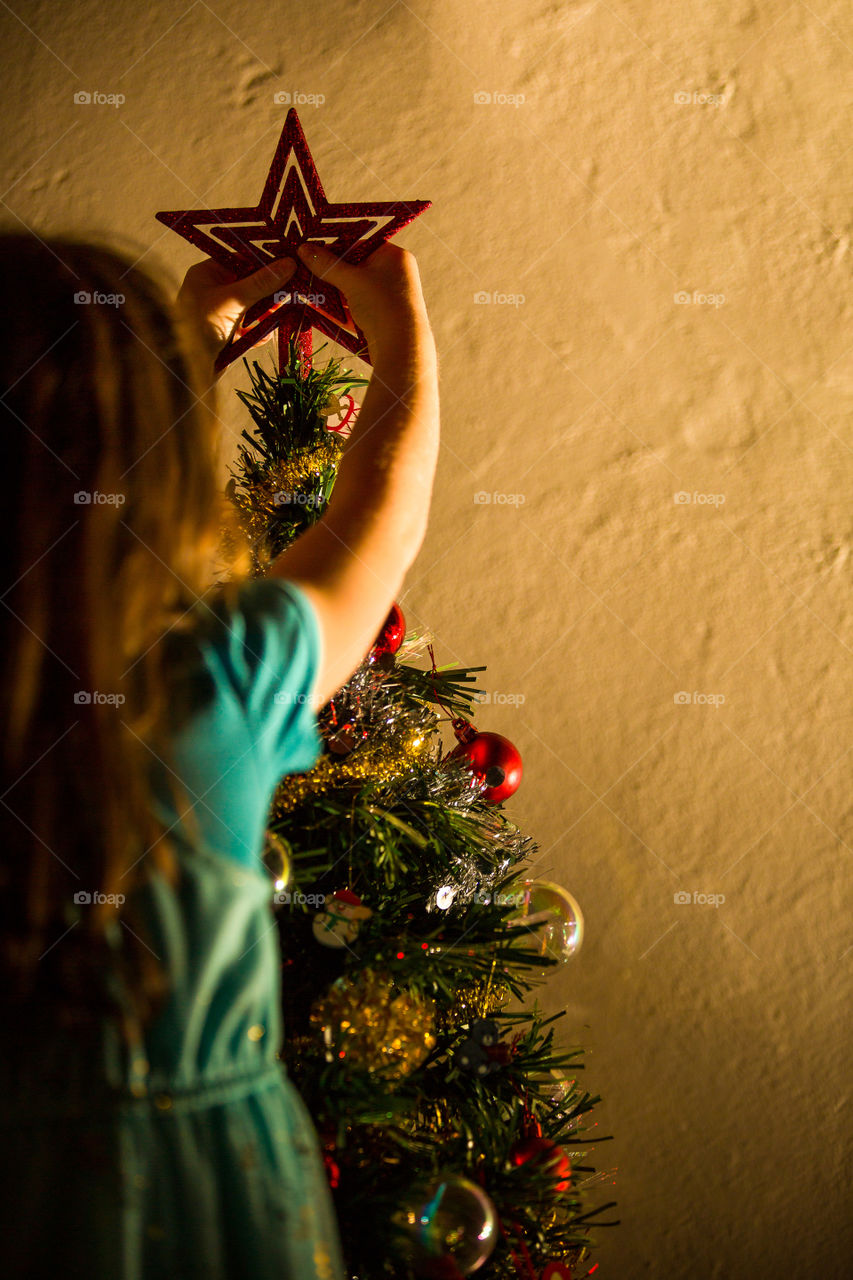 Christmas tradition to decorate the tree together. Image of my girl putting the star on the top of the Christmas tree.