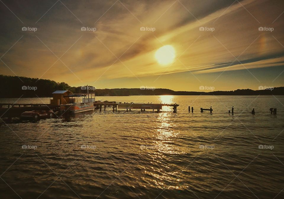 View of boathouse in lake at sunset