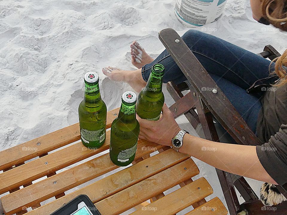 Woman relaxing in an arm chair on the sandy beach by the Gulf of Mexico enjoying friends and delicious tasting ice cold Heineken 