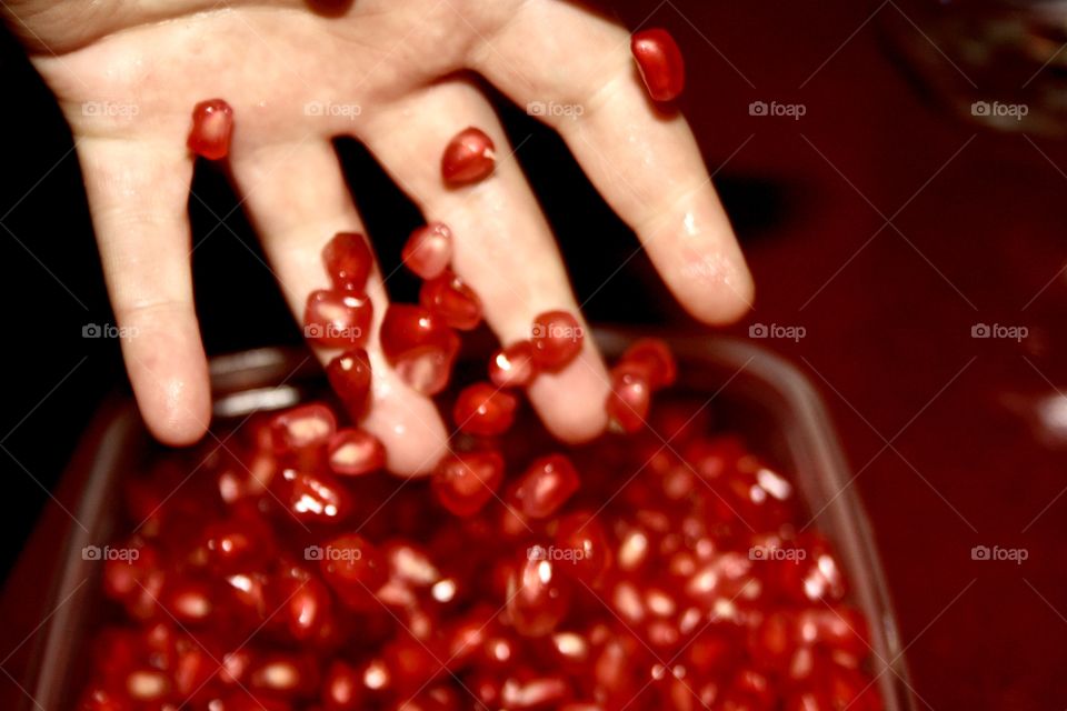 It is granada. The pomegranate is already peeled in a bowl. I reach in and grab a few seeds and drop them into the bowl.