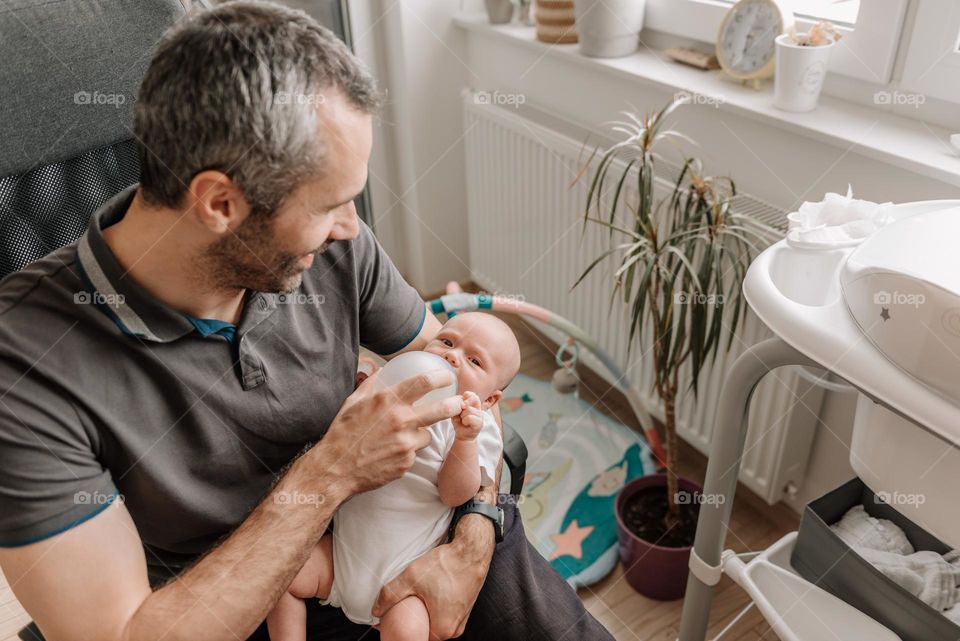 Father feeding baby son with bottle of baby formula