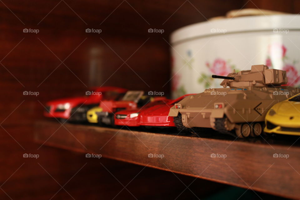 different toy vehicles stacked in a line on the shelf