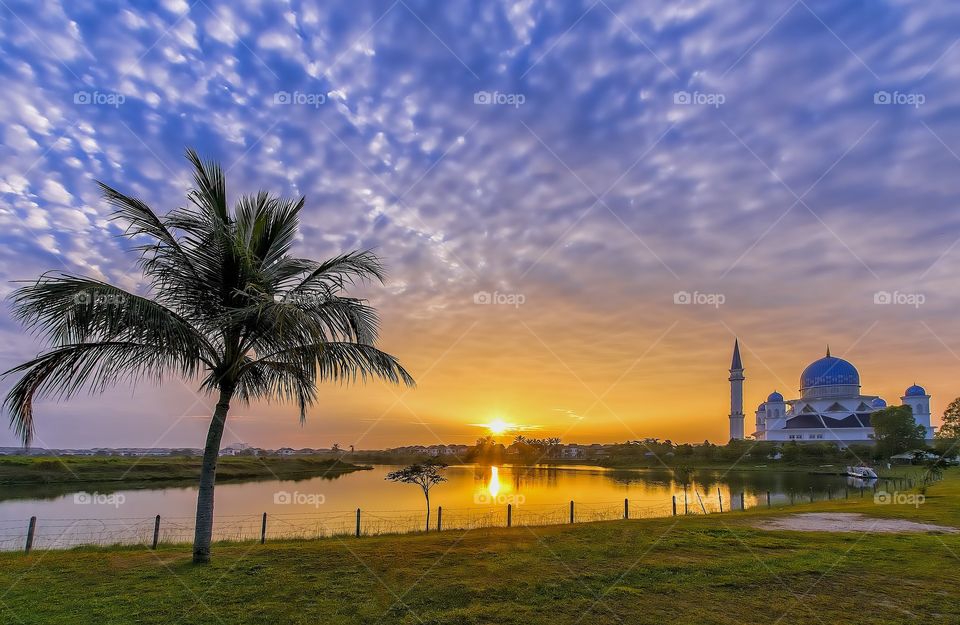 sunrise by the lake with blue dome mosque at background