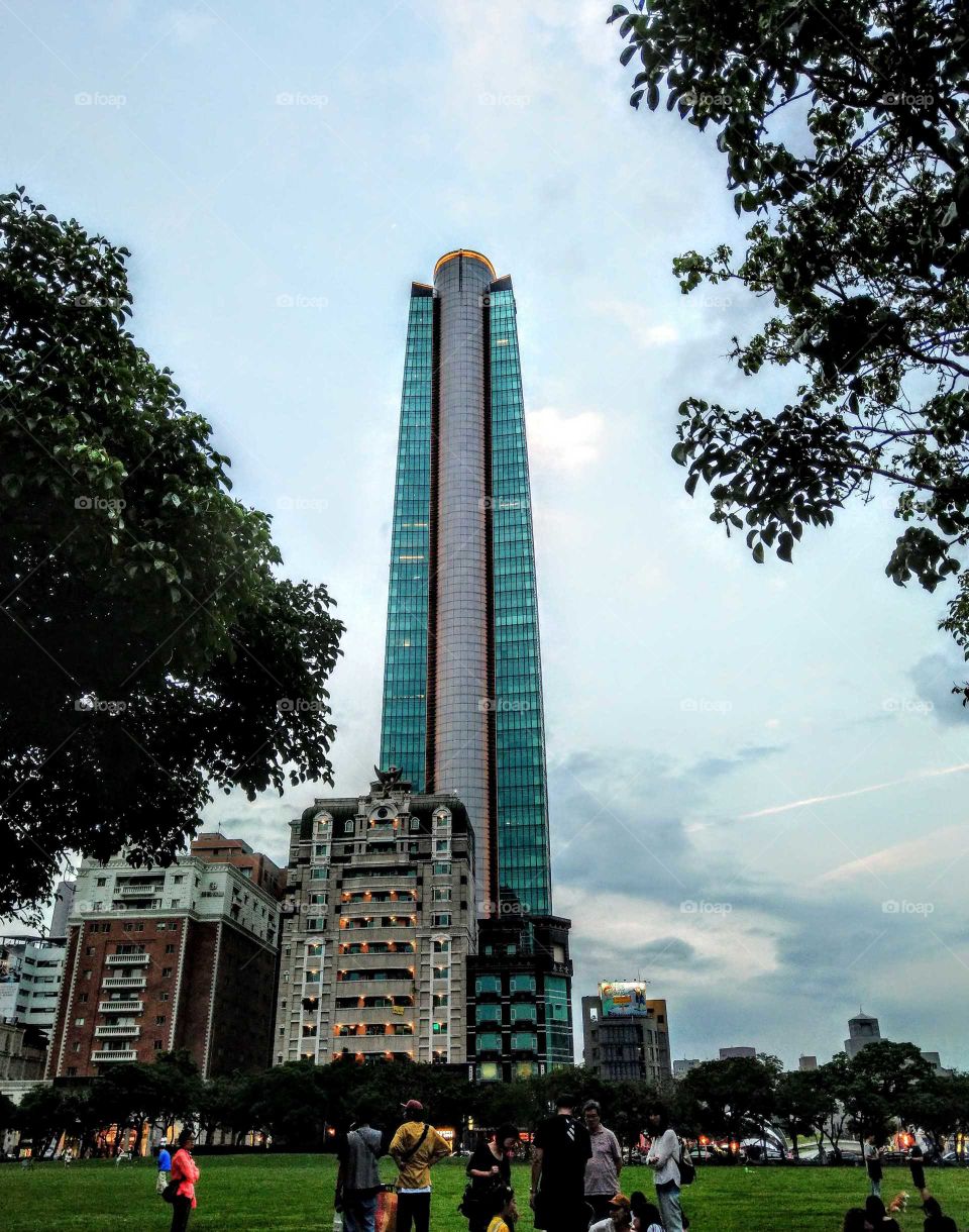 A beautiful building and people in the city park at the Sunday dusk. the day was coming to end, a happy ending to park activities.