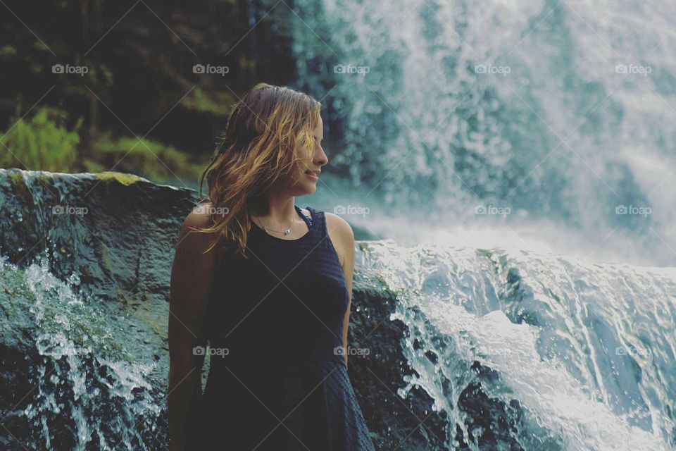A young woman exploring a wild waterfall