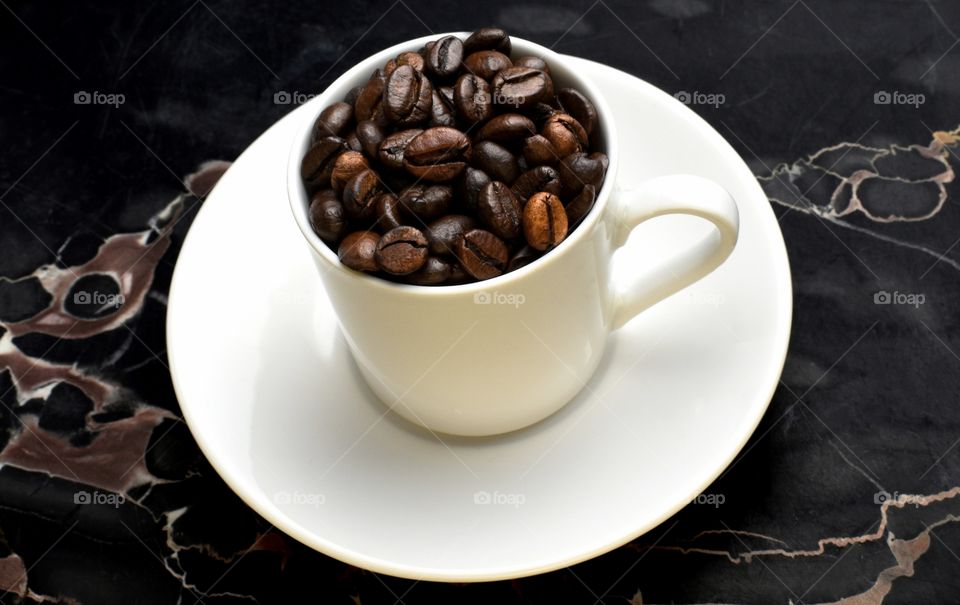 coffee beans in a white cup on marble background