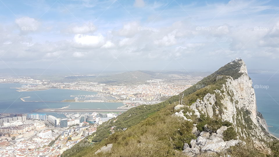 View from above, up high on The Rock of Gibraltar, Europe. Looking out towards city, ocean, and blue sky.