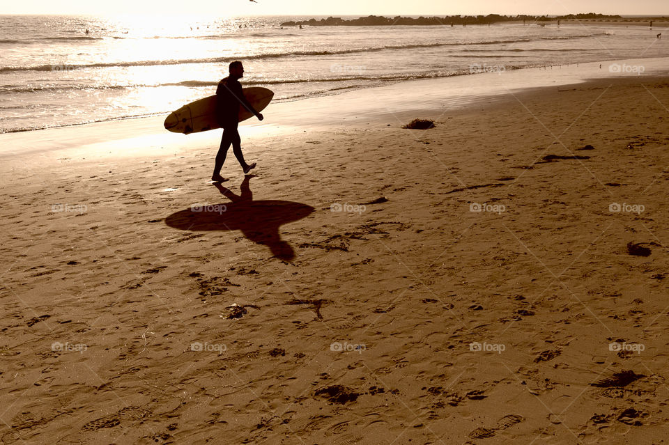 Surfer walking at sunset in Venice Beach