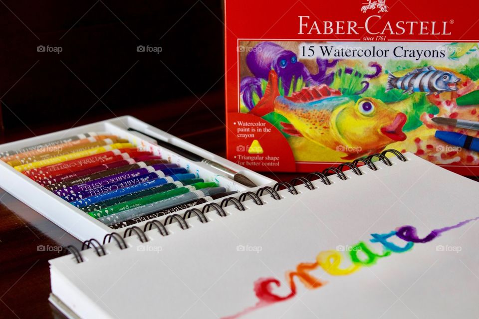 Colours of the World - watercolor crayons in white tray with brush, product box, and the word “create” on mixed media wire-bound paper