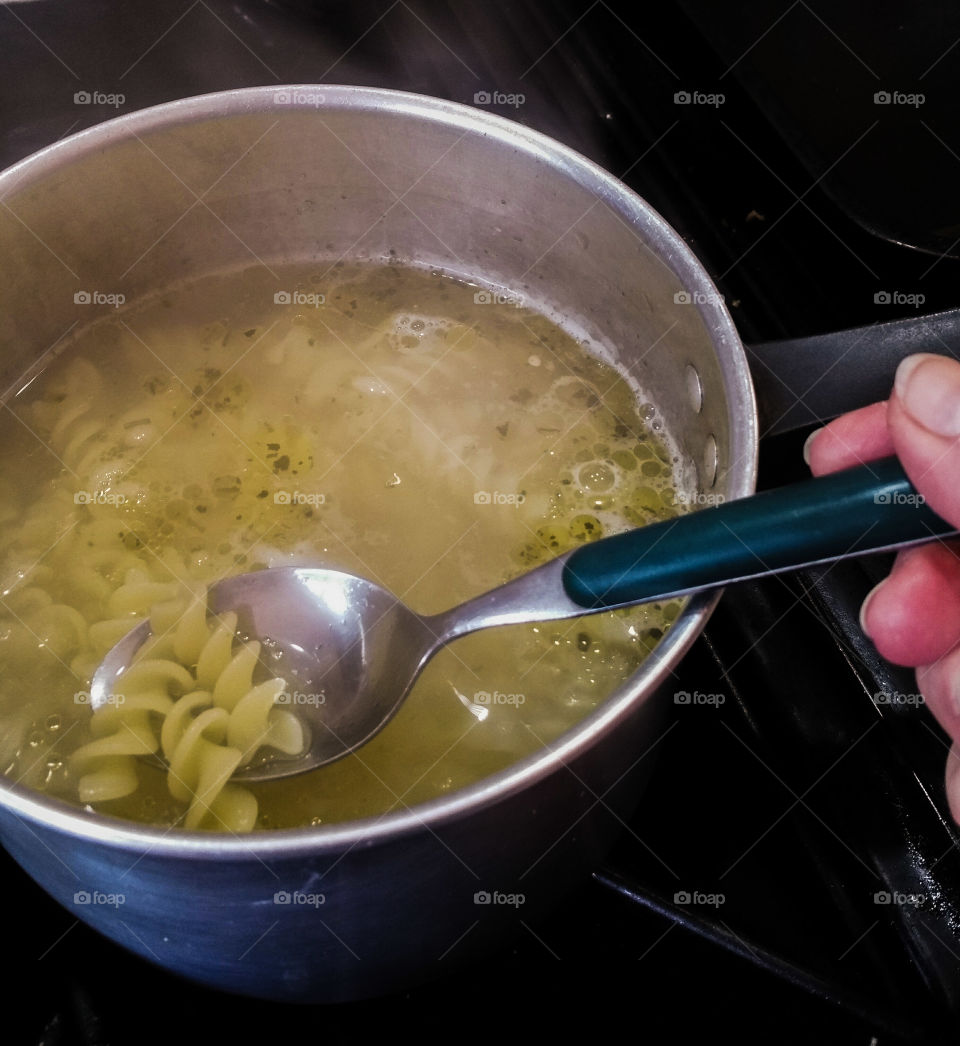 Cooking fusilli pasta with olive oil and herbs