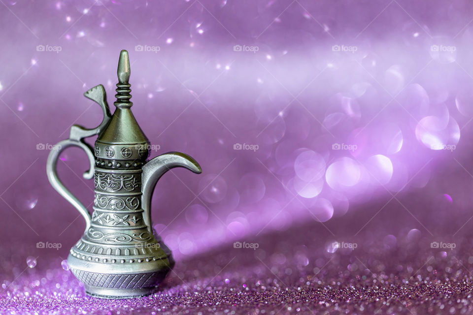 Arabic coffee pot on purple bokeh background, hospitality concept