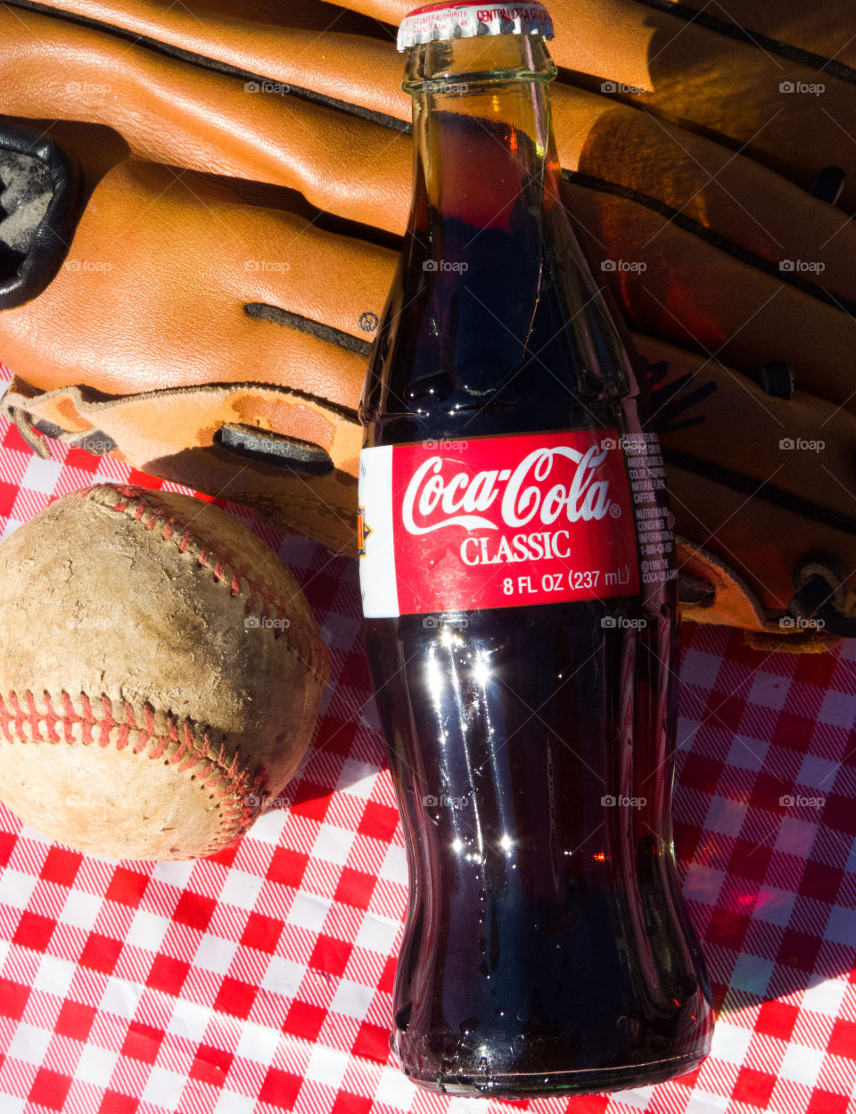 Classic Coca-Cola bottle with baseball and glove on a red checkered background.