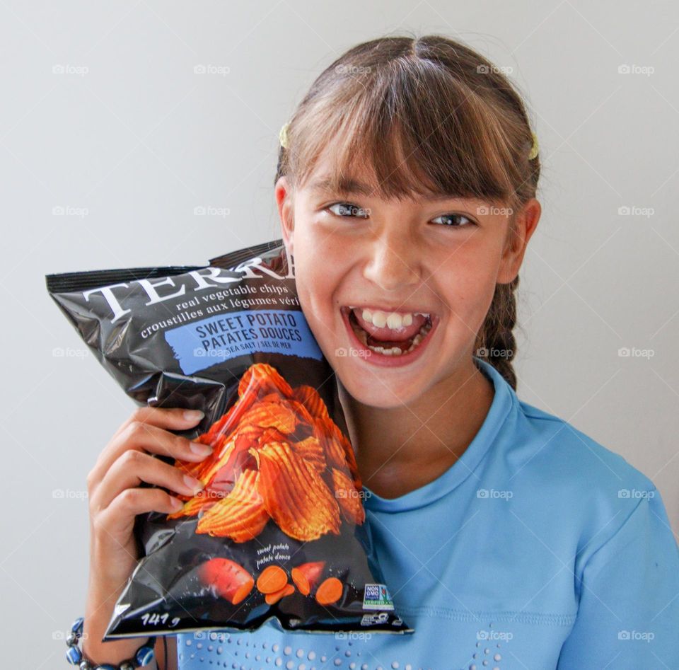 Cute happy girl with a bag of chips