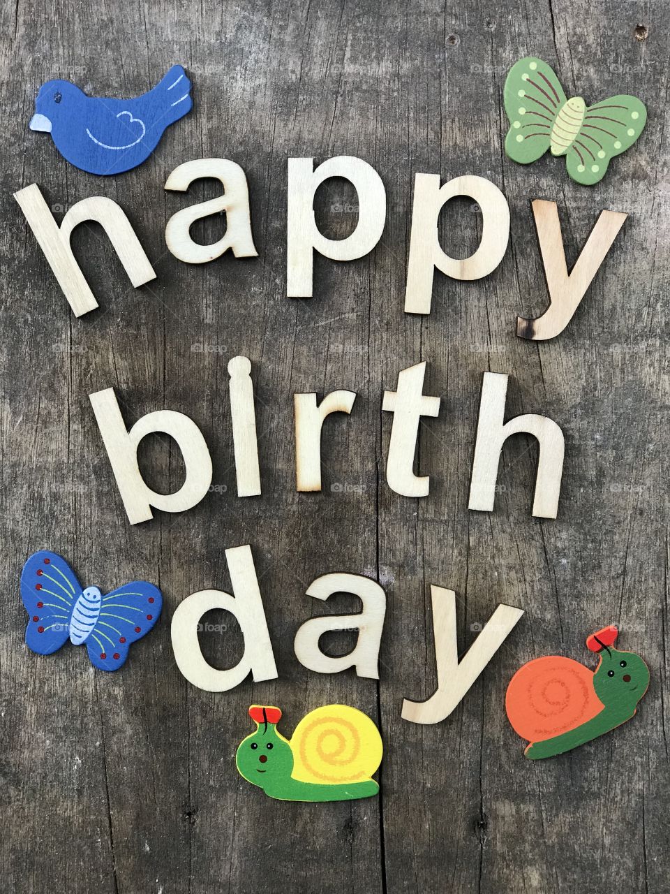 Happy Birthday text with wooden letters over a wooden board and artistic objects