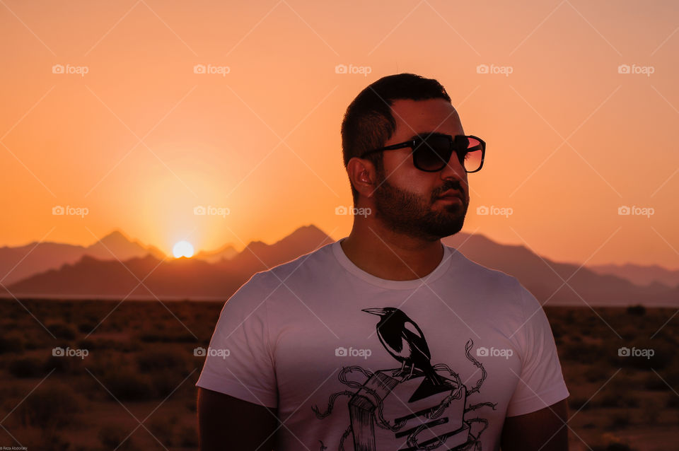 stylish fashion sunset. Offroad trip to the desert with a handsome guy wearing sunglasses sun is amazing in mountains and a beautiful red sky