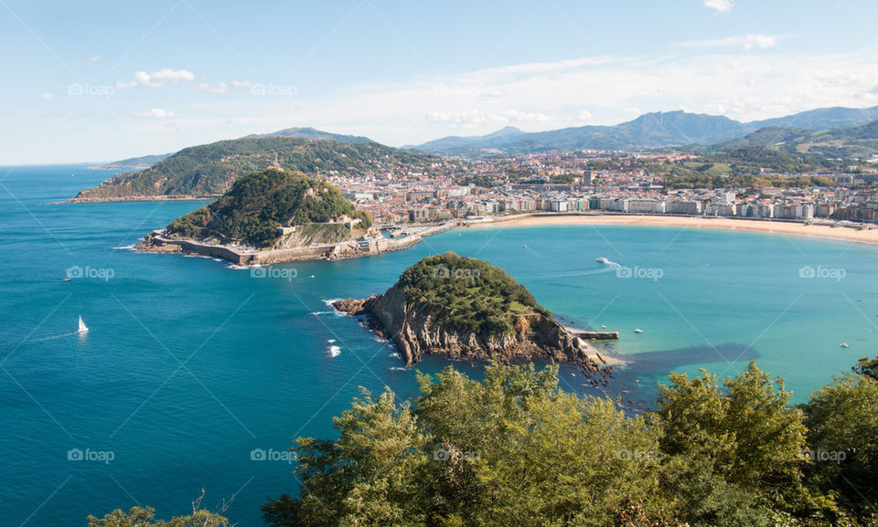 Scenic view of sea and mountains against clear blue sky