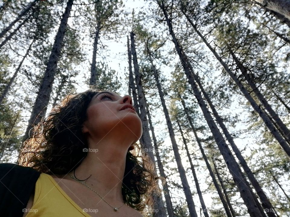 woman admires the beauty of nature looking at the treetops, after being in lockdown for weeks