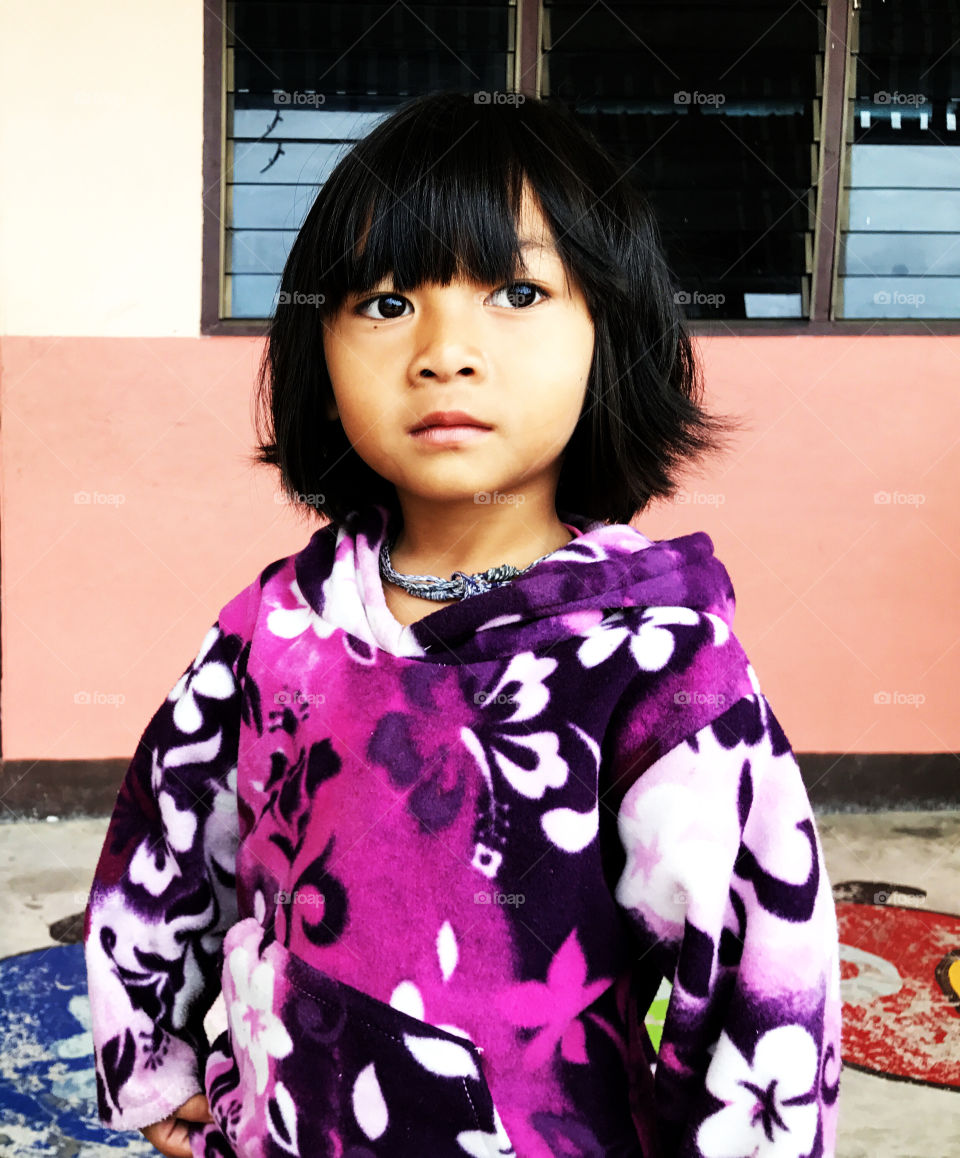 This girl has something in her eyes to touch my heart. She's shy but curious, looks afriad but brave. A child at school in top of mountain in Chaingmai, Thailand.