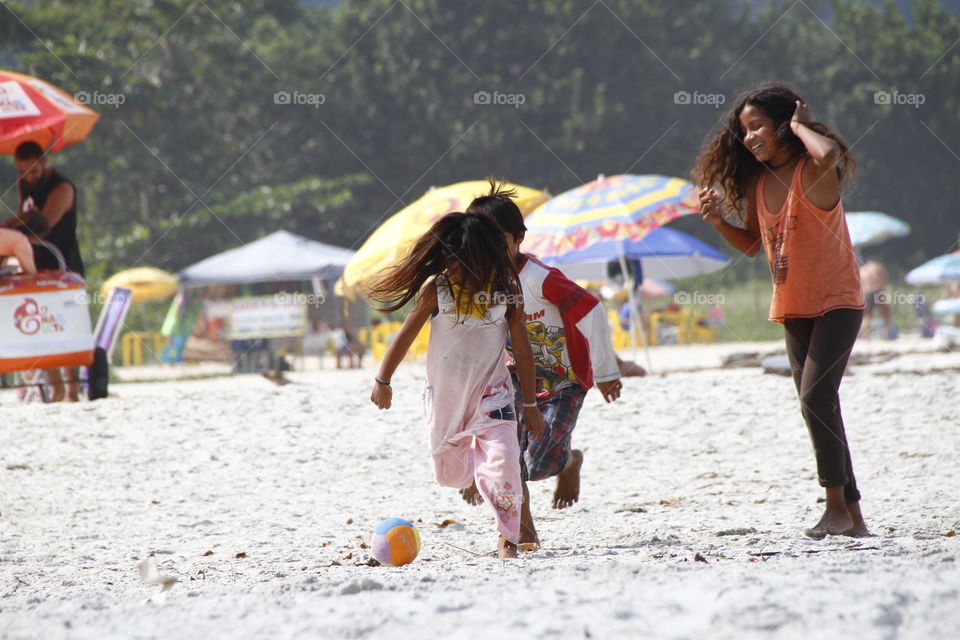 Brazilian indigenous children playing soccer on the beach