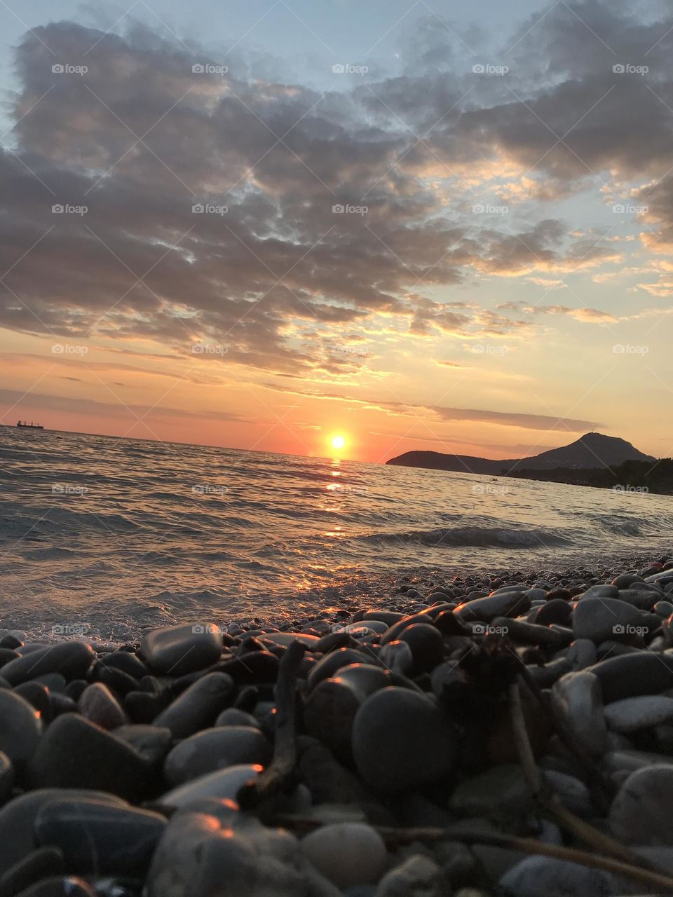 Sunset while the yellow sun is setting into the sea, and everything is peaceful and divine.