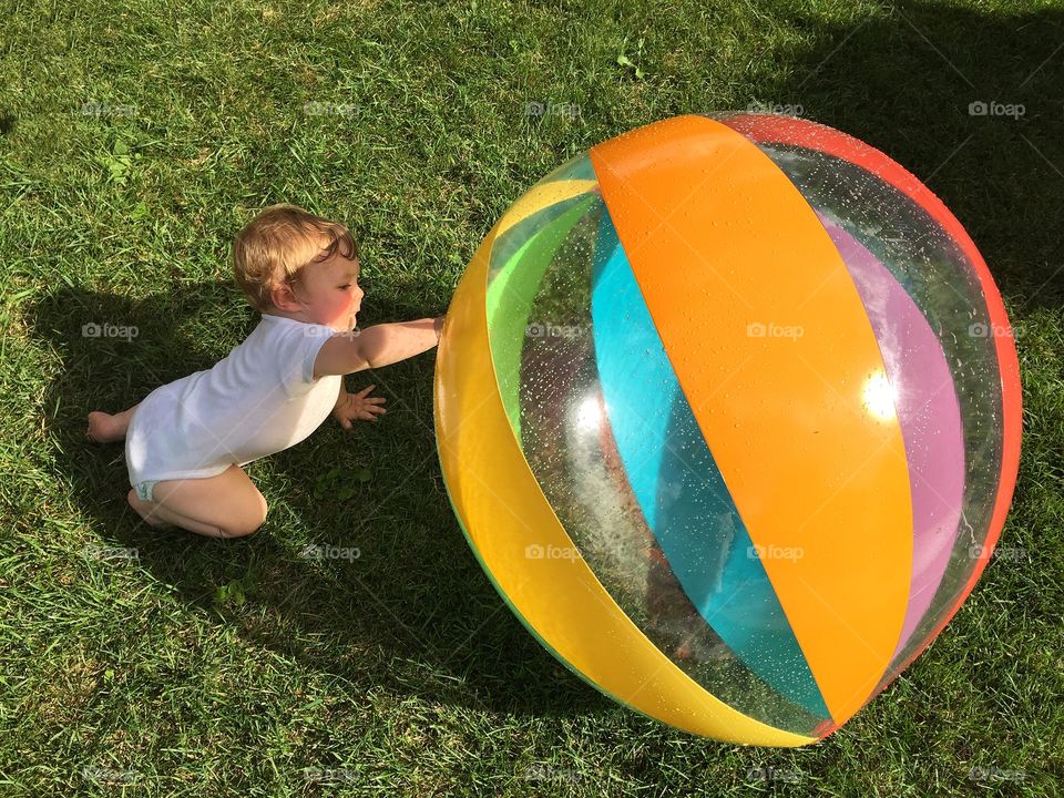 Toddler boy playing with big ball in park