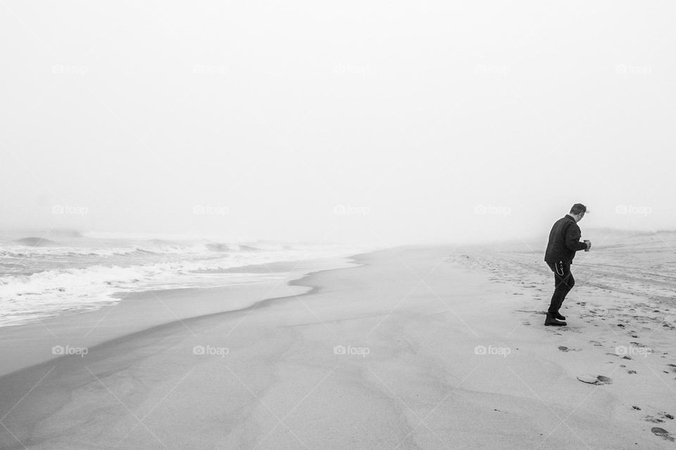 Monochrome image of man walking on beach, man pondering life on a beach, on a beach in New York walking, walking on a Long Island beach 