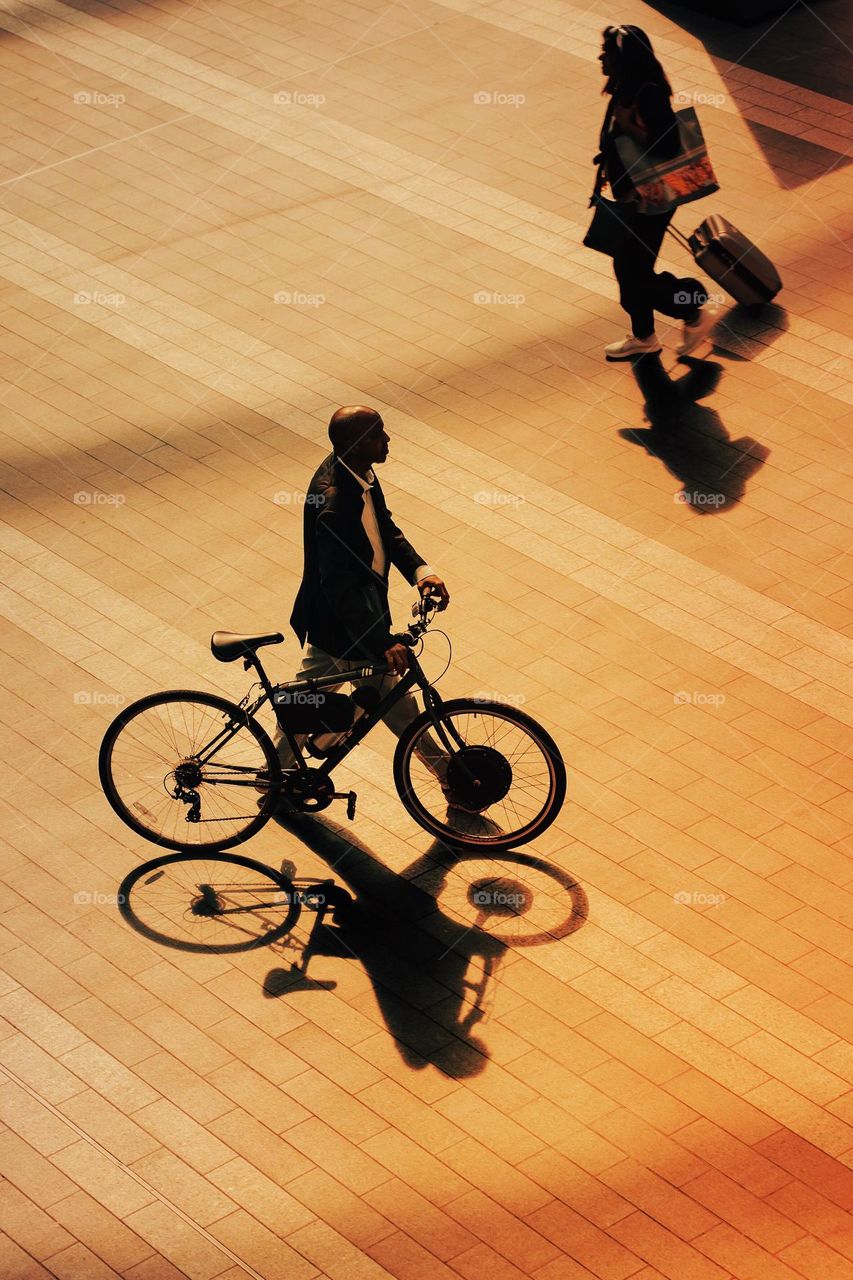 Aerial view of a male commuter pushing his bicycle in a city environment 