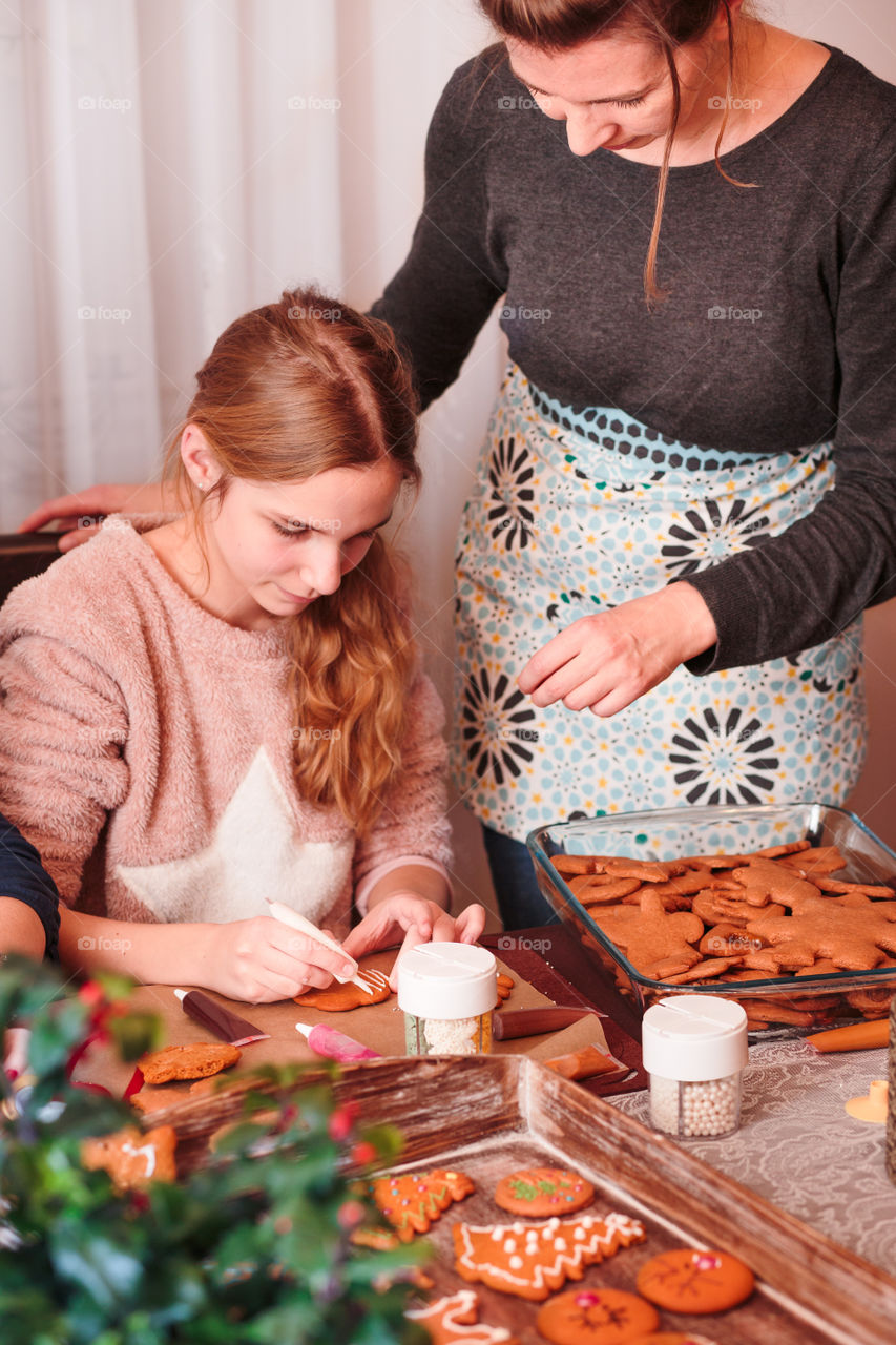 Girl decorating baked Christmas gingerbread cookies with frosting writing pen