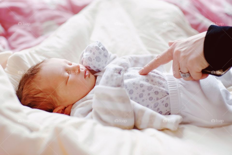 Baby kid sleeping on bed and mother finger