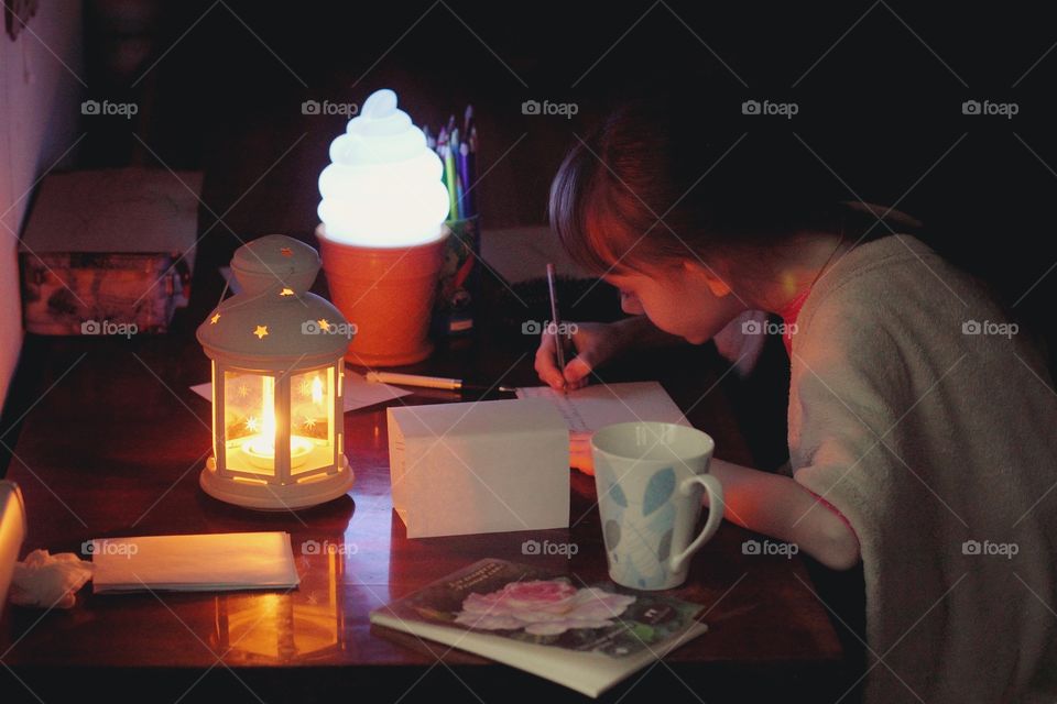 A girl writes a letter on a December evening