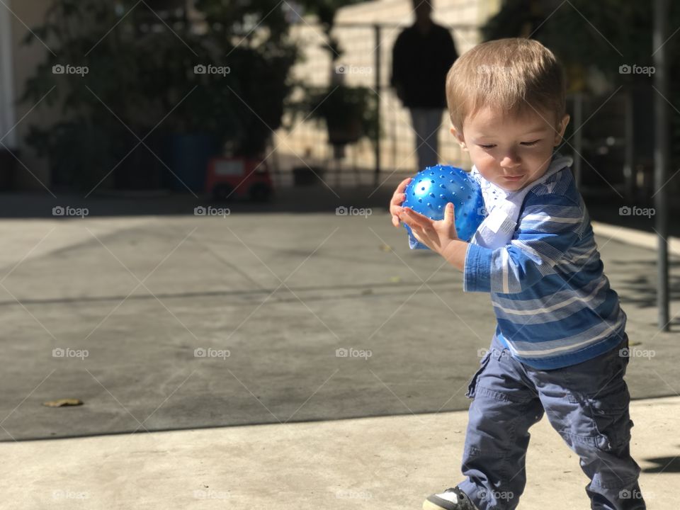 Small kid playing with blue ball at outdoors