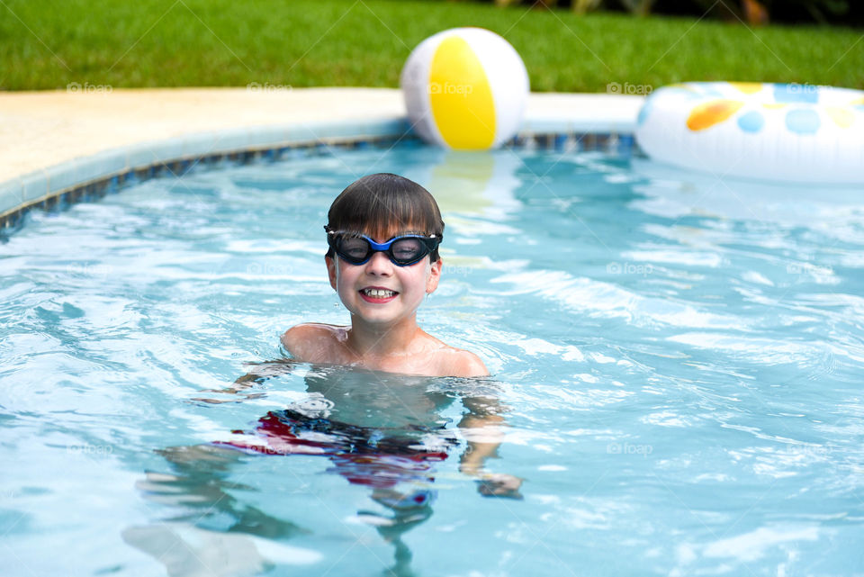 Young smiling boy wearing goggles in a swimming pool