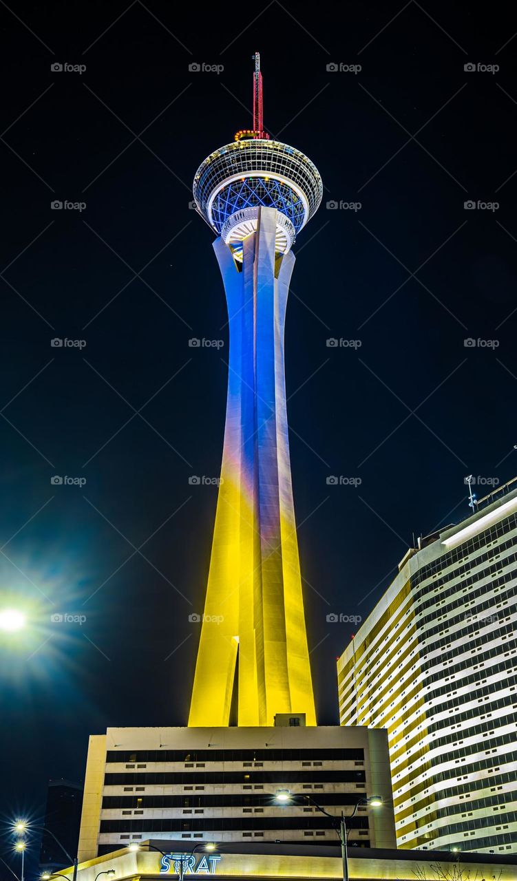 The STRAT (formerly the Stratosphere) lit in blue and yellow, the colors of Ukraine. Barely ever changing its colors, this is a bold statement coming from the casino hotel. Captured in long exposure at night from Downtown Las Vegas.