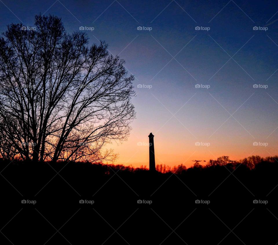 distant view of monument silhouette against orange and blue sky at sundown