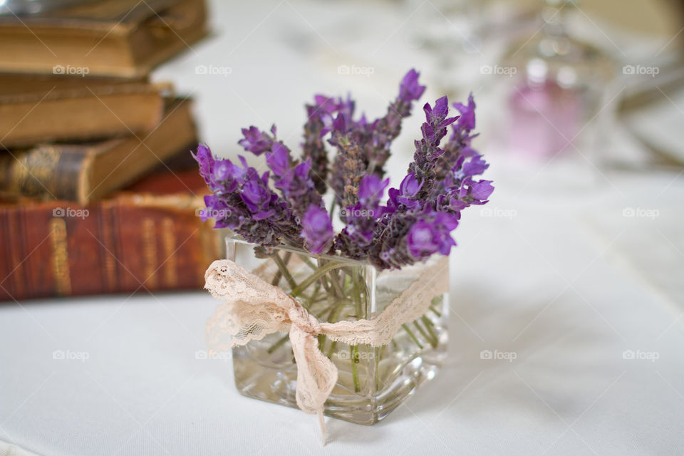 Square vase with lavender and books in the background. Rectangles and squares on different forms such as the flowers in this image