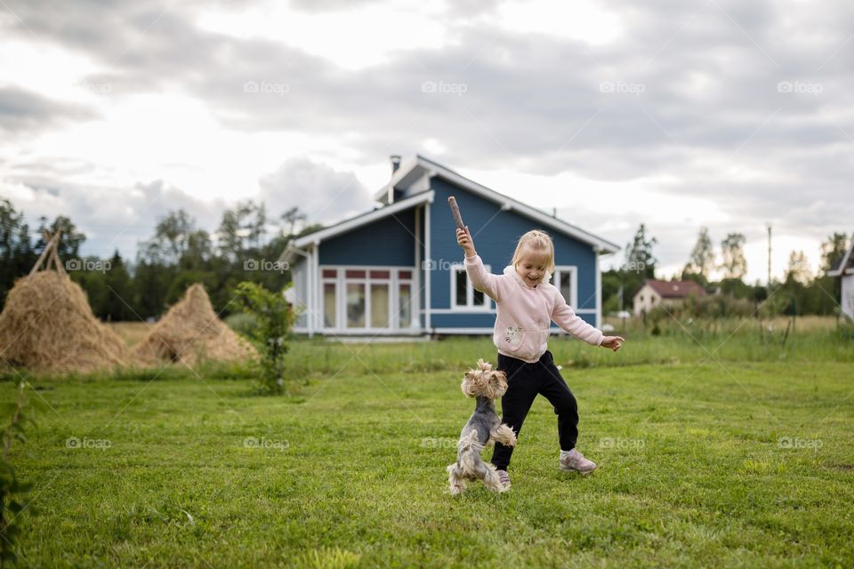Little girl playing with dog on backyard 