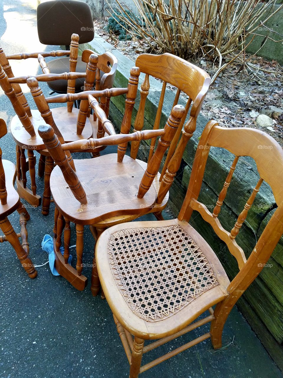 Yard sale chairs, one with caning on the seat.