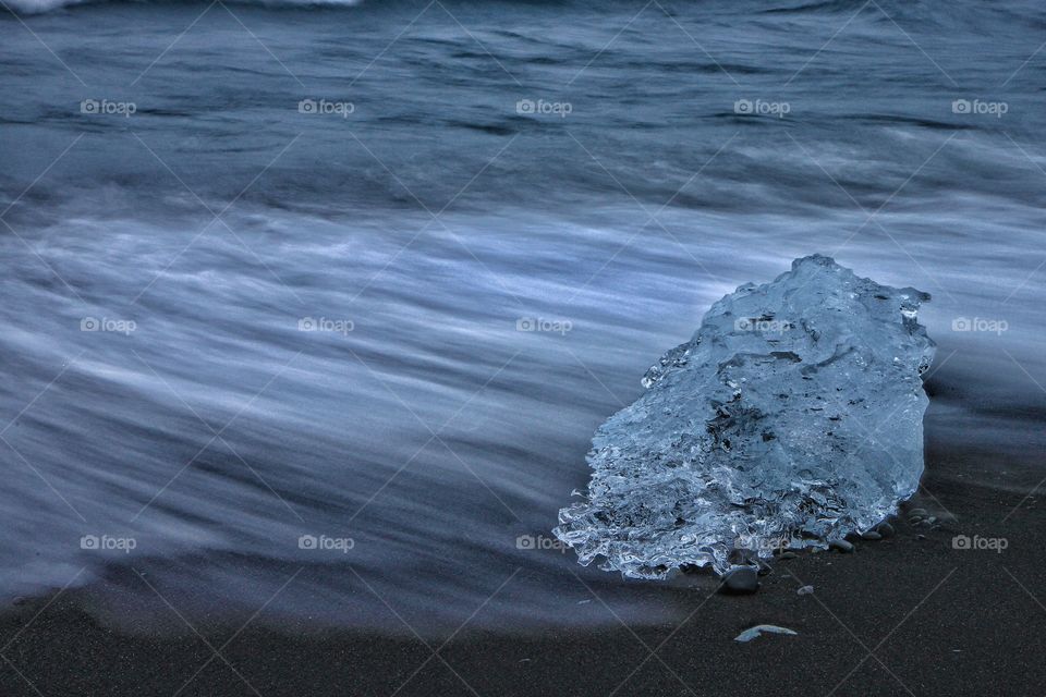 Glacial ice on black beach in the breaking waves