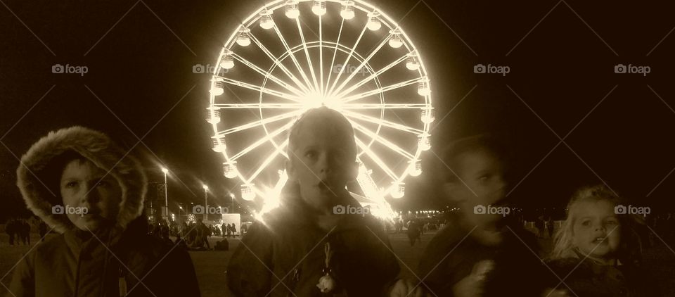 Group of children's in front of illuminated ferris wheel