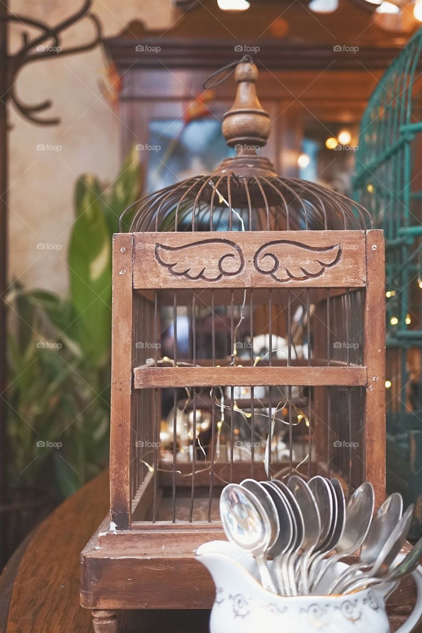 Vintage wooden bird cage with selective focus on the wings carved on wood