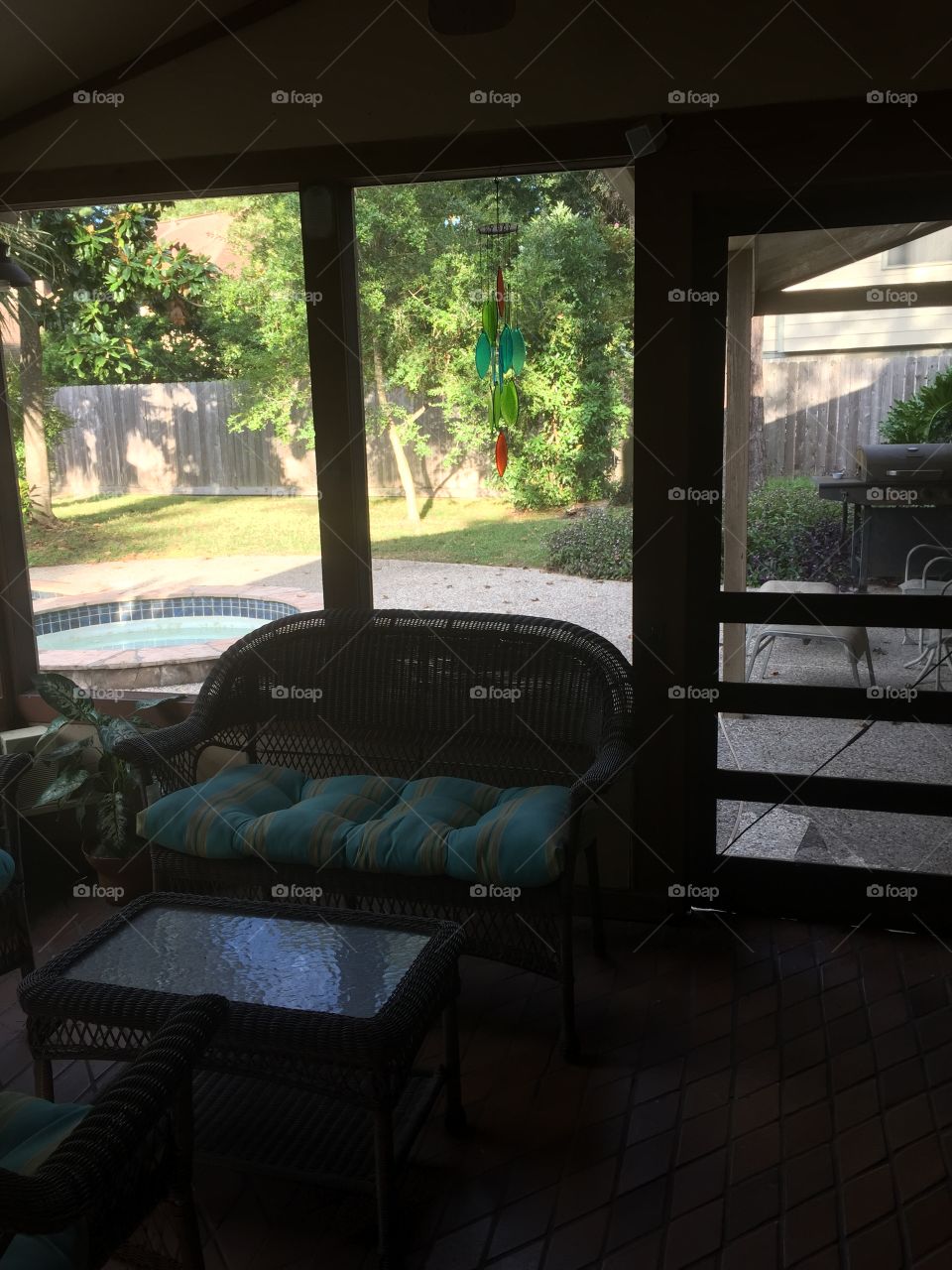 Blue and green wind chimes match the cushions, pool, trees, grass, and other plants. 