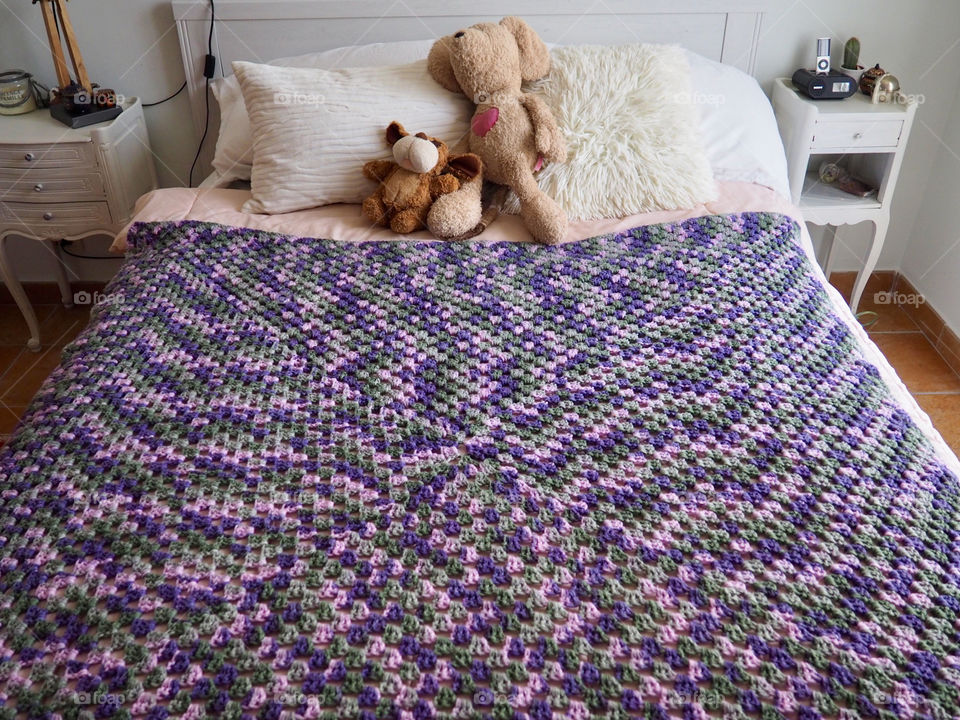 Shades of purple hand made crochet blanket on girl’s bed.