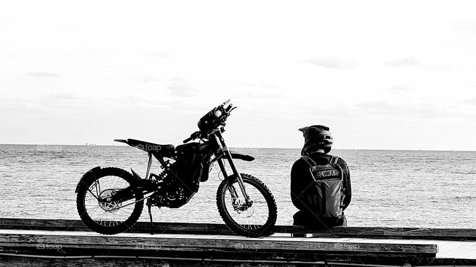 Motorbike rider relaxing at the coast.
