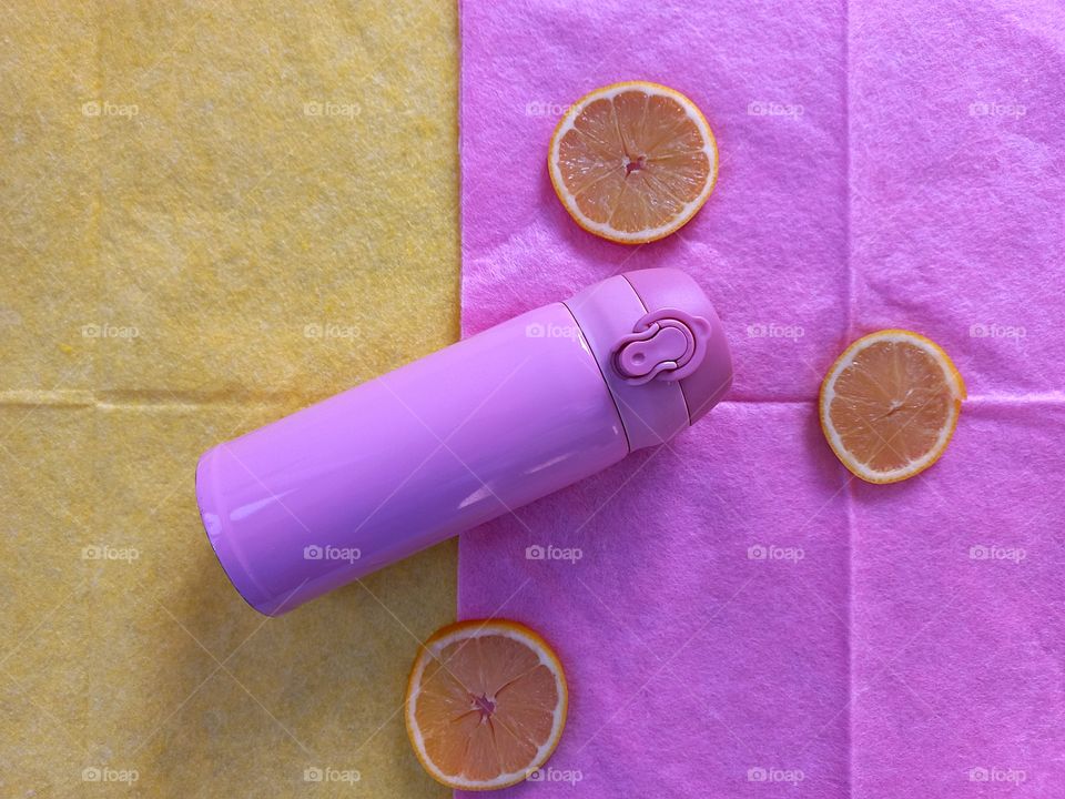 a combination of pink and a yellow-pink thermo mug on the background of a yellow napkin and slices of yellow lemon on the background of a pink napkin!