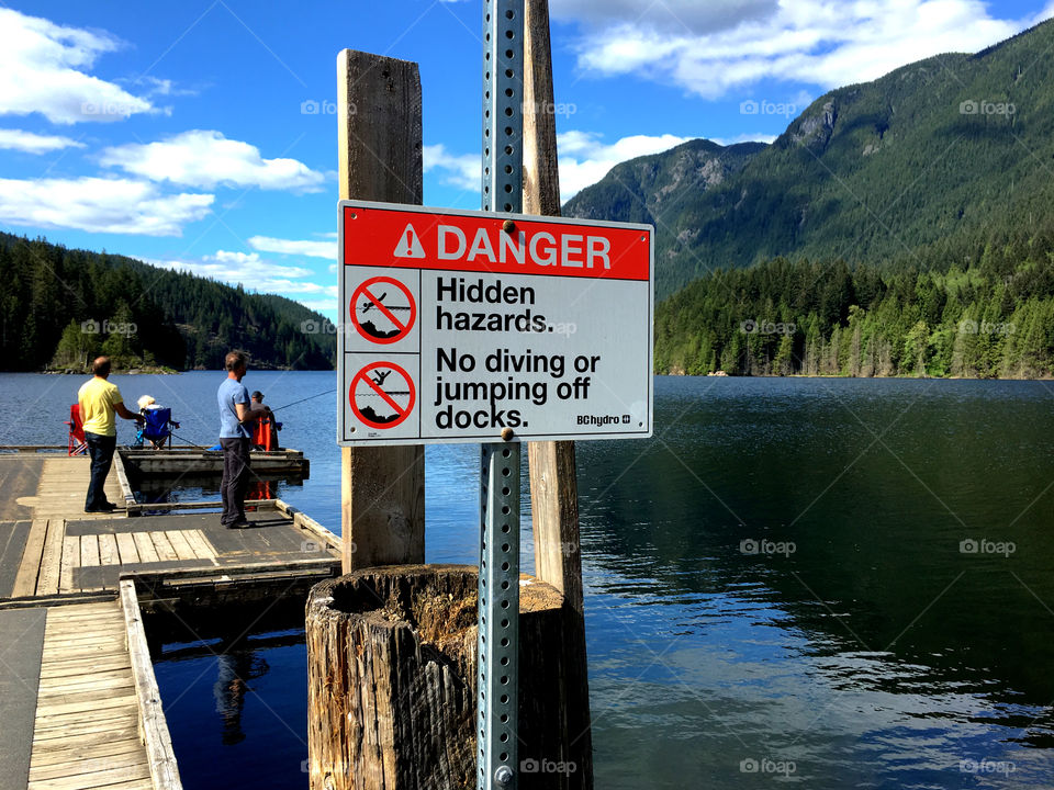 Fishing at the lake and hazard sign
